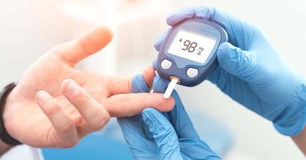 physician using a blood glucose monitor to monitor patient's blood sugar